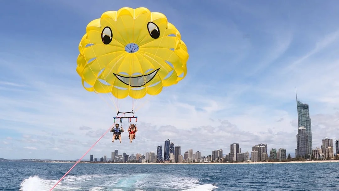 Parasailing over ocean with city skyline in background, Jet Ski & Parasail Experience.