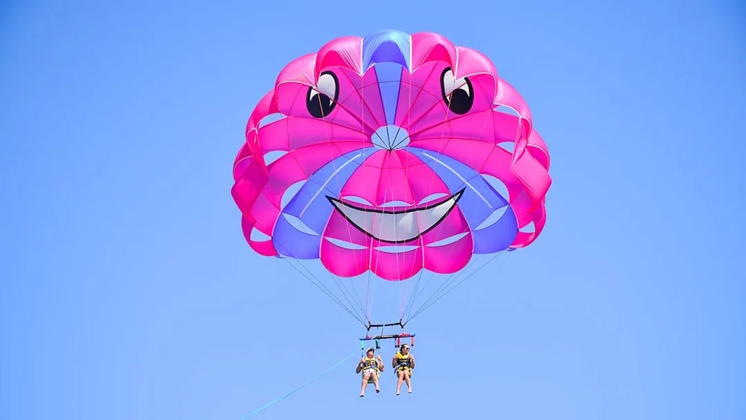 Parasailing with colorful parachute against clear blue sky.