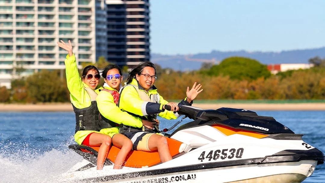 Family enjoying a jet ski ride near city waterfront.