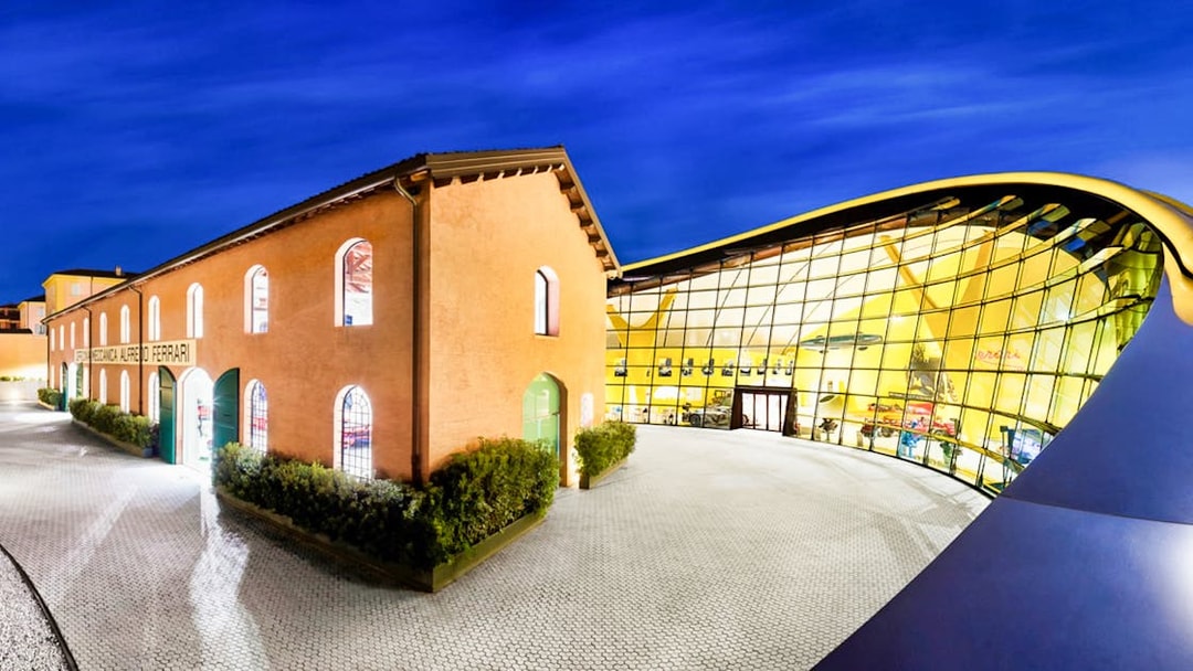 Museo Enzo Ferrari Modena entrance with modern glass facade at night.
