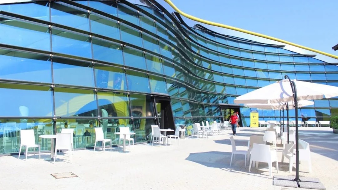 Exterior view of Museo Enzo Ferrari Modena with modern glass facade and outdoor seating.