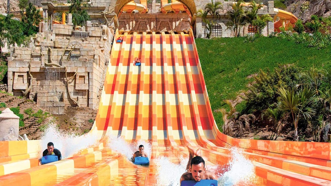 Water slide at Aqualand Maspalomas with people racing down on mats.