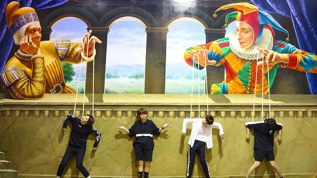 Visitors pose as marionettes in front of a puppet-themed mural at Art in Paradise Pattaya.