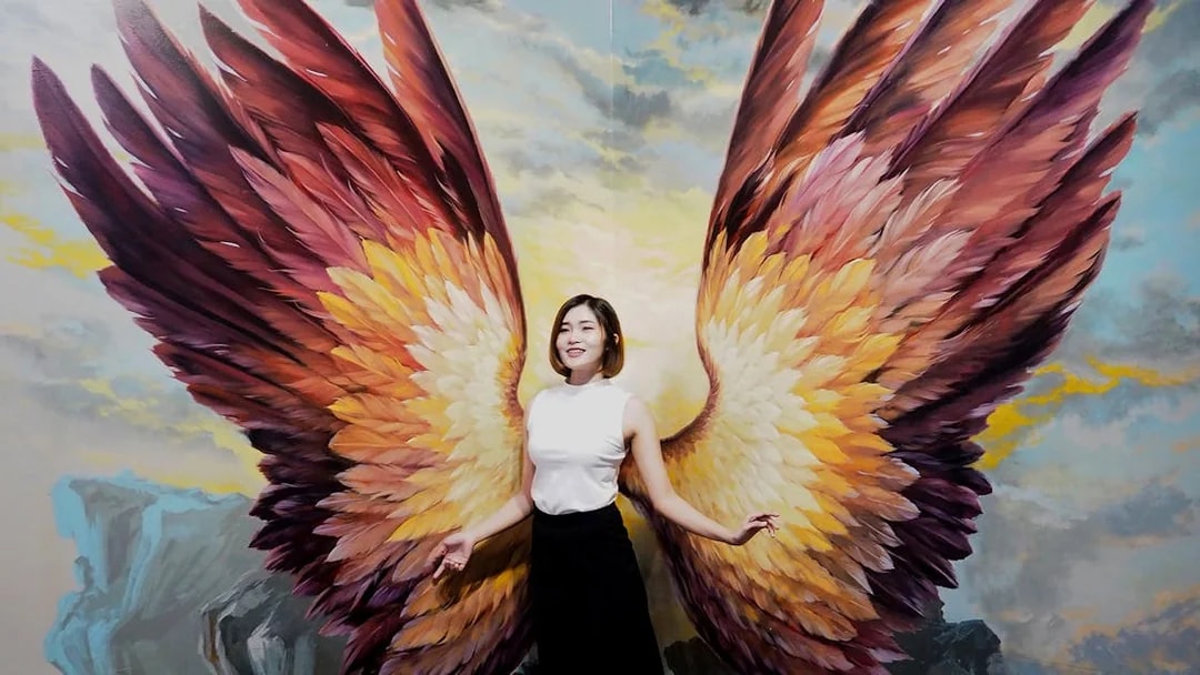 Person posing with angel wings mural at Art in Paradise Pattaya.