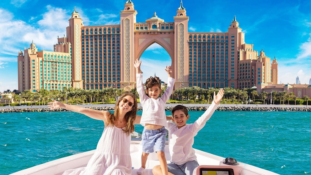 Family enjoying Atlantis Scenic Cruise with Atlantis The Palm in Dubai in the background.