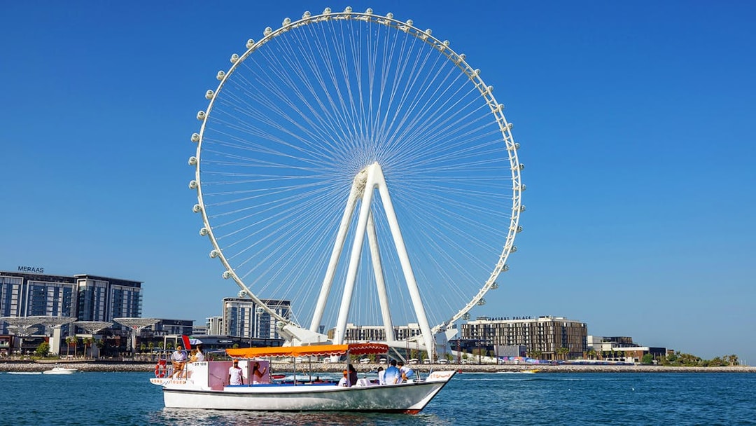 Boat cruising near Ain Dubai Ferris wheel on Atlantis Scenic Cruise in Dubai.