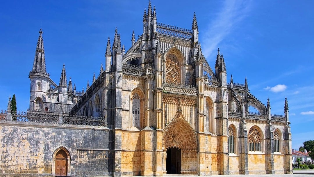 Batalha Monastery's intricate Gothic facade under a clear blue sky, Lisbon.