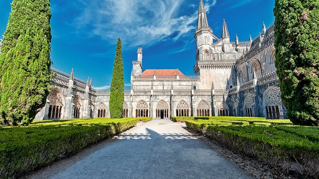 Abbey of Batalha Monastery with Gothic architecture and manicured gardens in Portugal.