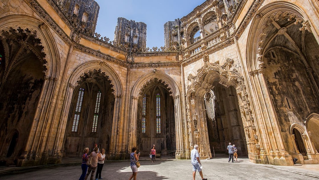 Visitors exploring the Gothic architecture of Batalha Monastery, Portugal.