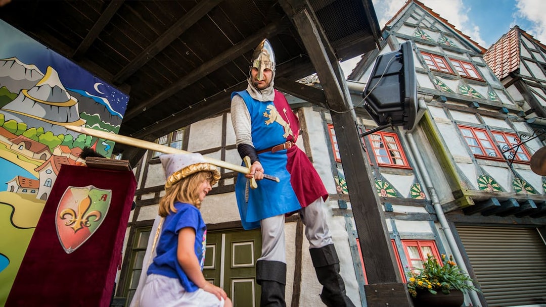 Knight performing at Belantis Adventure Park musical show with child on stage.