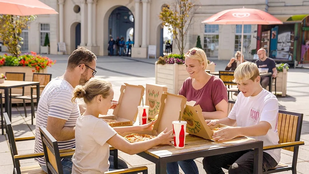 Family enjoying pizza at an outdoor table in Belantis Adventure Park.