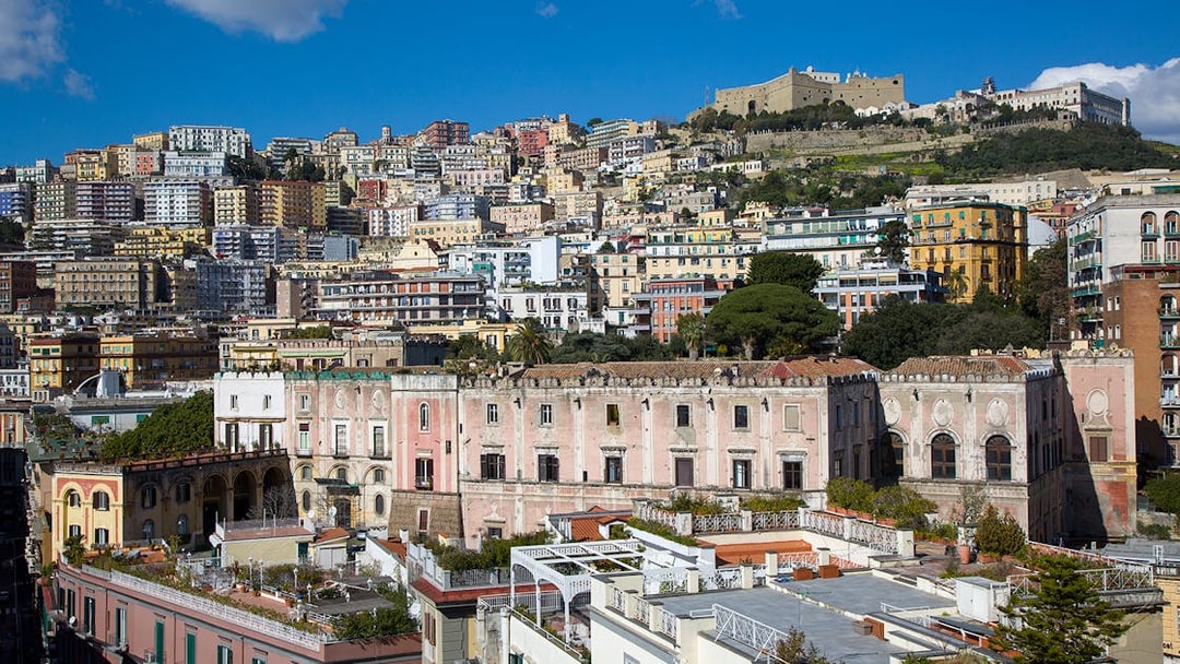 View of Castel Sant'Elmo atop a hill in Naples, Italy, with colorful buildings below.