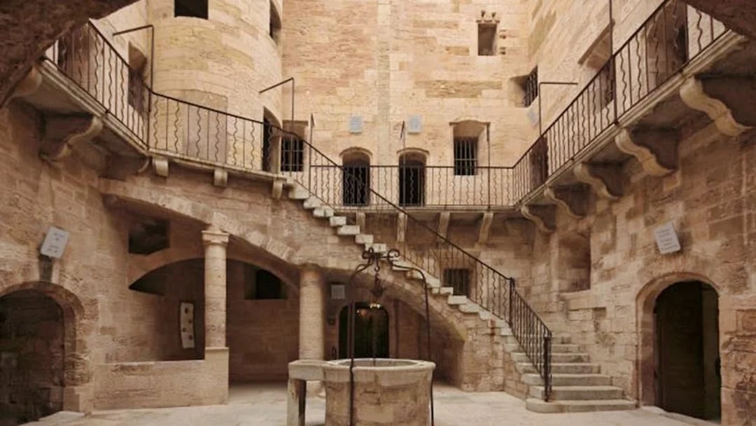 Château d’If courtyard with stone staircase and central well in Marseille, France.