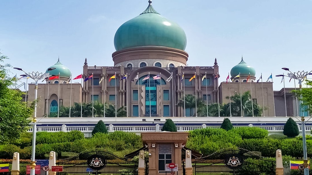 Putrajaya's Perdana Putra building with flags, seen on a traditional boat cruise.