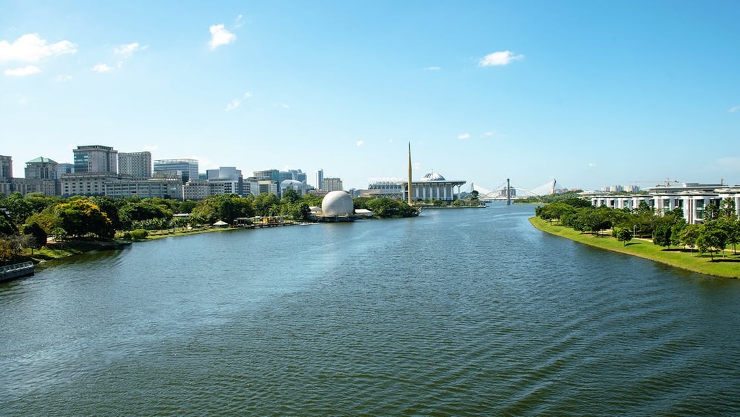 Putrajaya skyline with river view, featuring modern architecture and lush greenery.