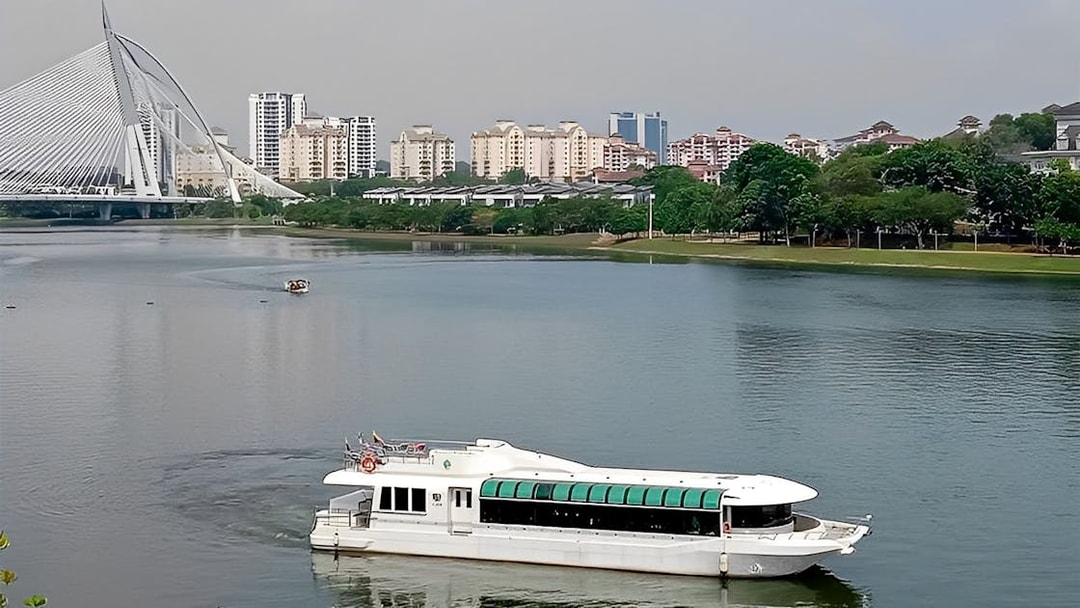Cruise boat on Tasik Putrajaya with city skyline and bridge in the background.