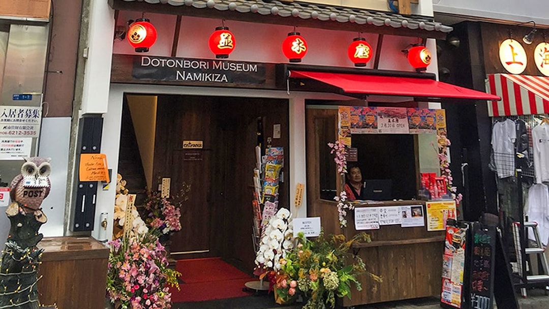 Entrance to Osaka Dotonbori Museum Namikiza with ticket booth and red lanterns.