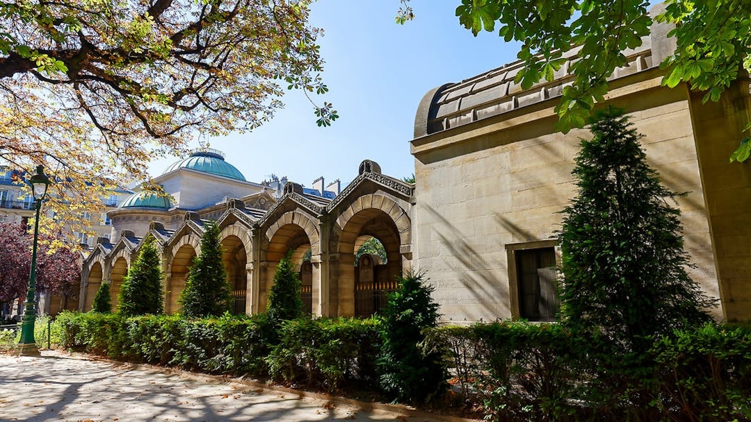 Expiatory Chapel exterior with arches and greenery in Paris, France.