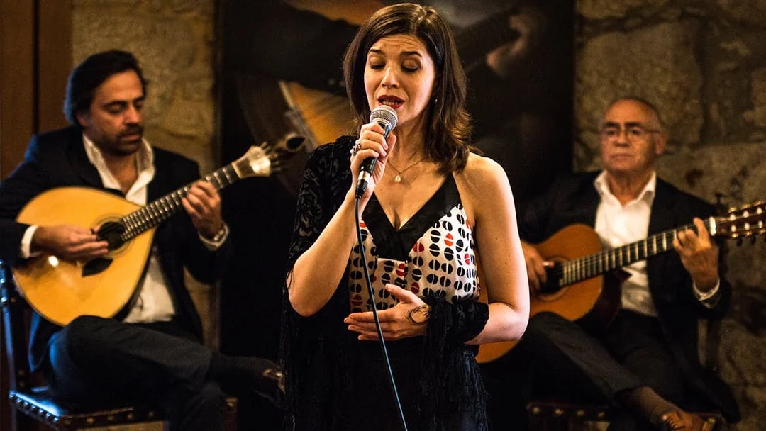 Fado singer performing with guitarists in a Port wine cellar.