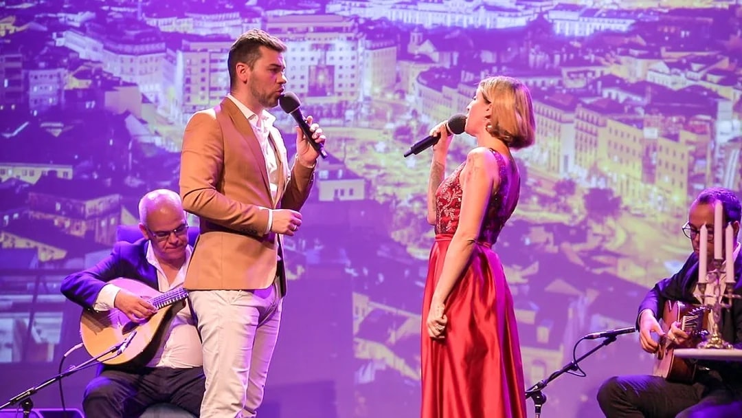 Fado singers performing on stage in Chiado, Lisbon with musicians playing guitars.
