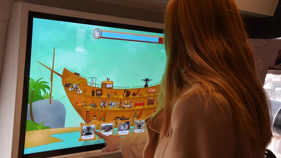 Interactive display of Frigate D. Fernando II e Glória with a person engaging with the touchscreen.