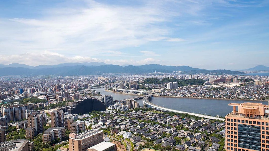Aerial view of Fukuoka cityscape with river and mountains, seen from Fukuoka Tower.