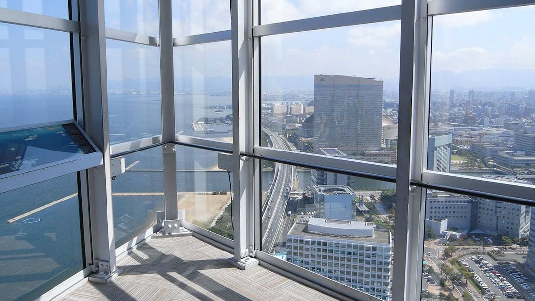 View from Fukuoka Tower observation deck overlooking cityscape and coastline.