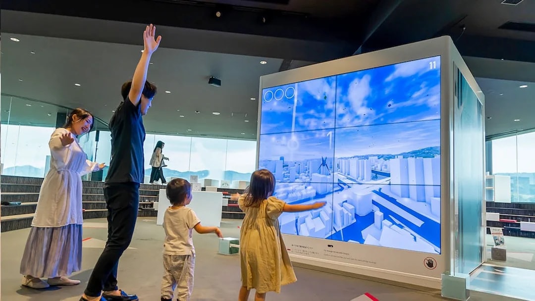 Visitors interacting with a digital display at Hiroshima Orizuru Tower.