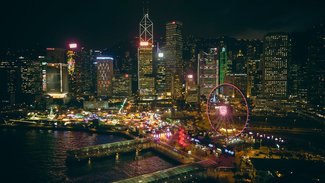 Hong Kong skyline at night with illuminated Observation Wheel and waterfront.