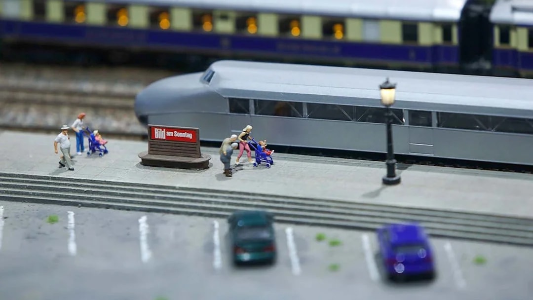 Miniature railway scene with people and strollers near a train at Hzero.