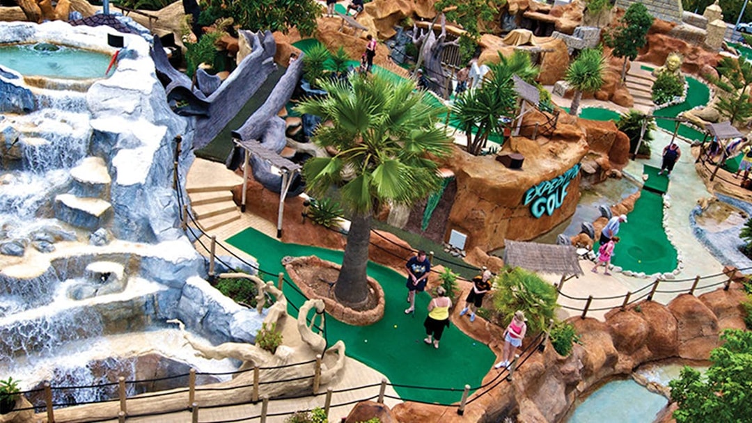 Mini-golf course at Katmandu Park with waterfalls and tropical landscaping.