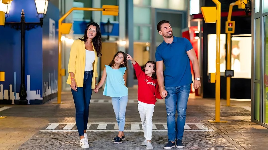 Family walking through KidZania Abu Dhabi, children pointing at attractions.