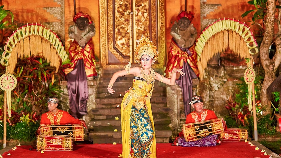 Dancer performing Legong dance at Ubud Palace, Bali with musicians in traditional attire.