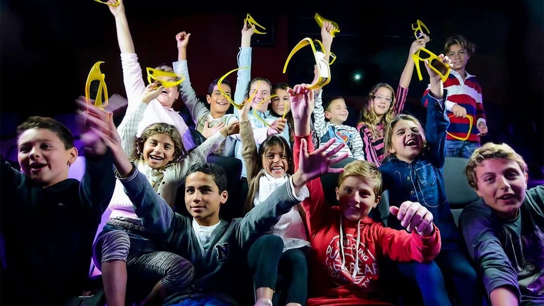 Children enjoying Malta 5D audio-visual show with 3D glasses in hand.