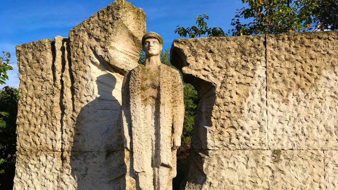 Statue of a soldier at Memento Park, Budapest, surrounded by textured stone.