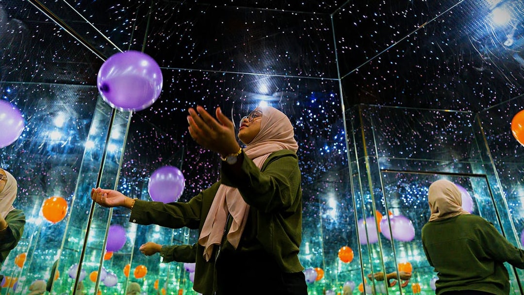 Person in mirrored room with balloons at Museum of Illusions Kuala Lumpur.