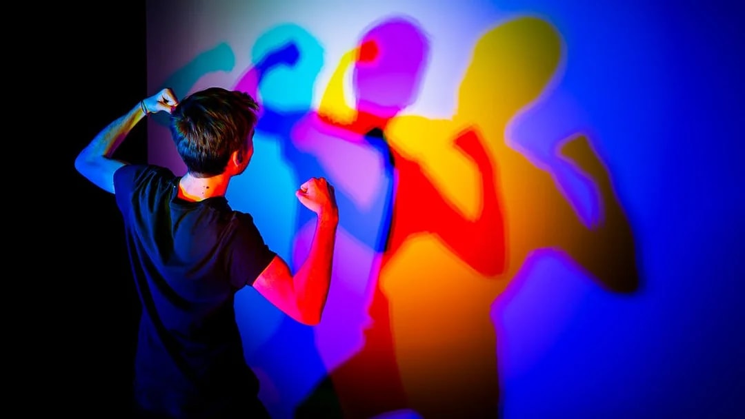 Person interacting with colorful shadows at Museo de las Ilusiones Sevilla.