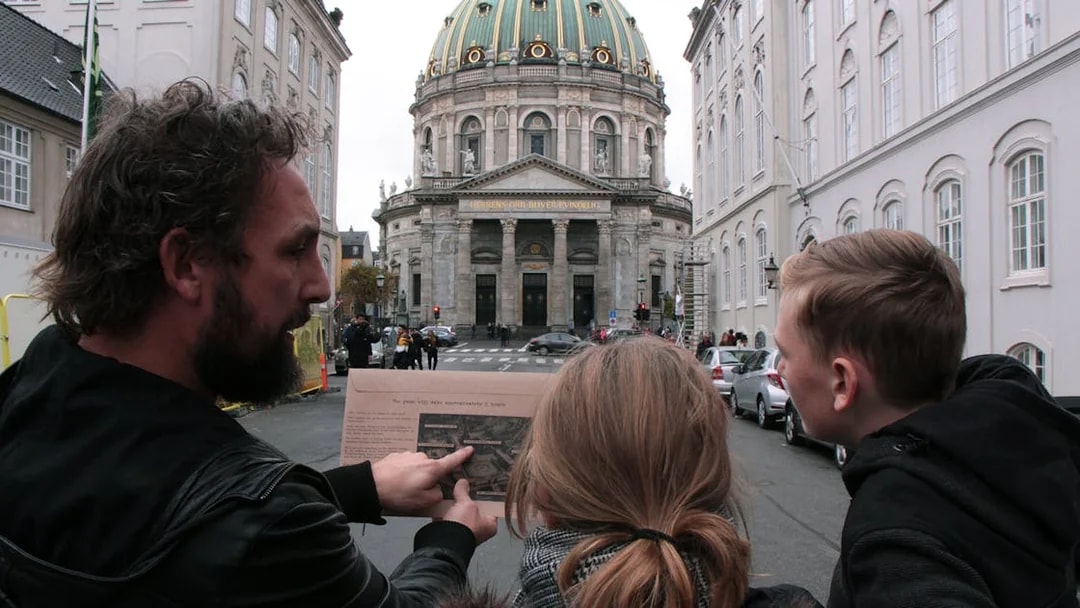 Participants in a mystery hunt near Amalienborg Palace, Copenhagen, examining a map.