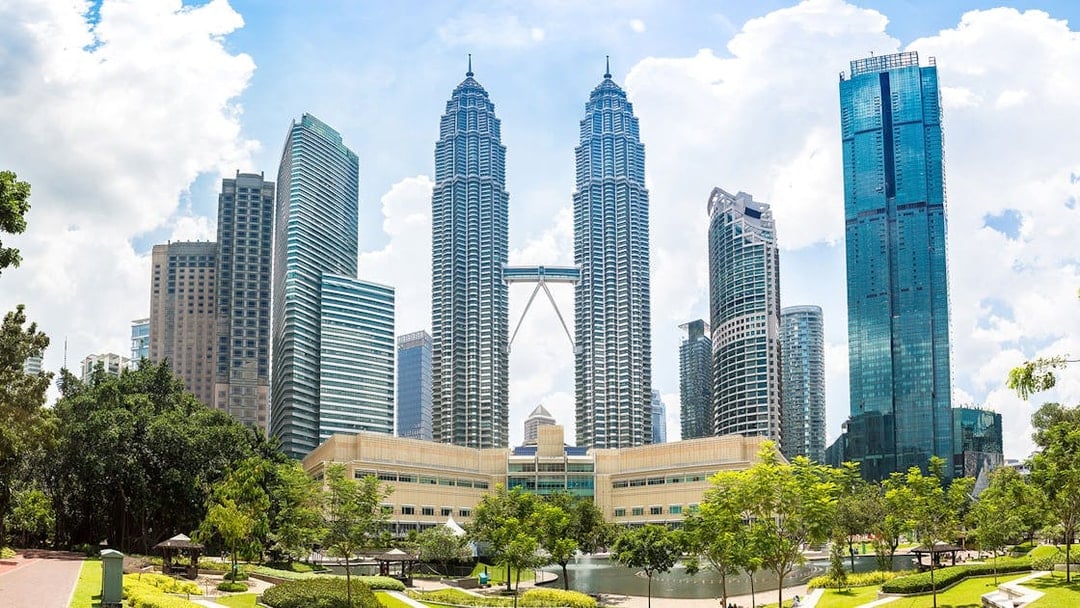 Petronas Twin Towers in Kuala Lumpur with surrounding skyscrapers and park.