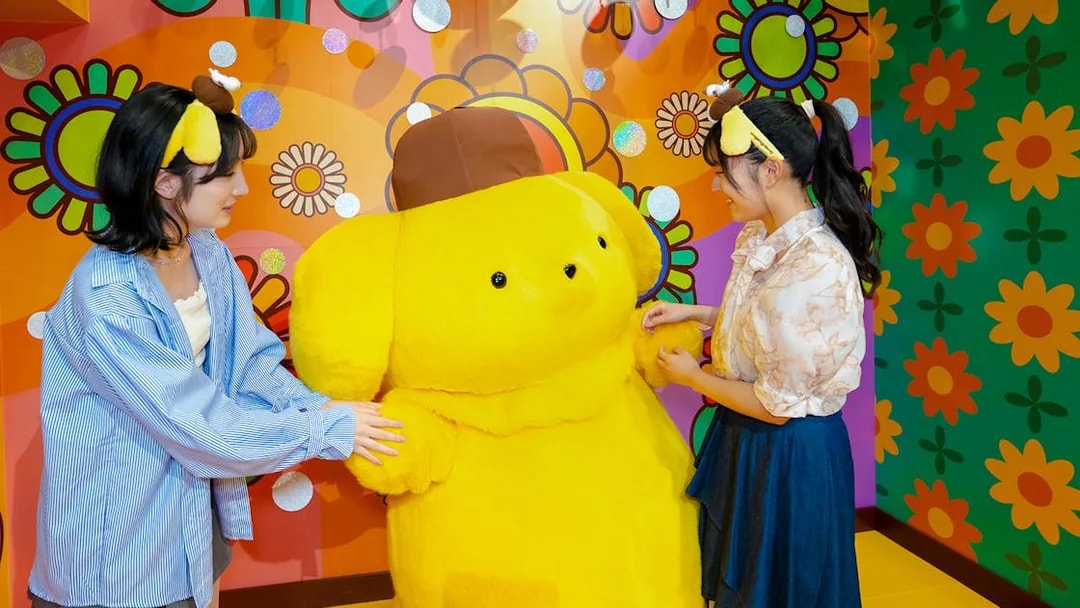 Visitors interacting with a large yellow character at Sanrio Puroland.