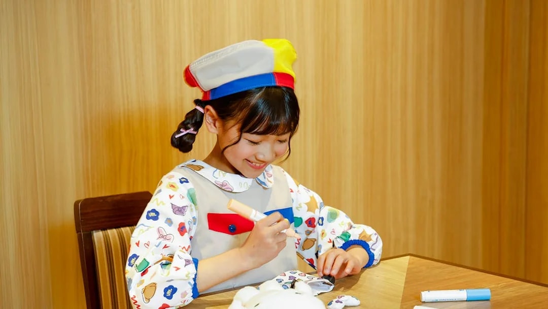 Child coloring a plush toy at Sanrio Puroland, Japan.