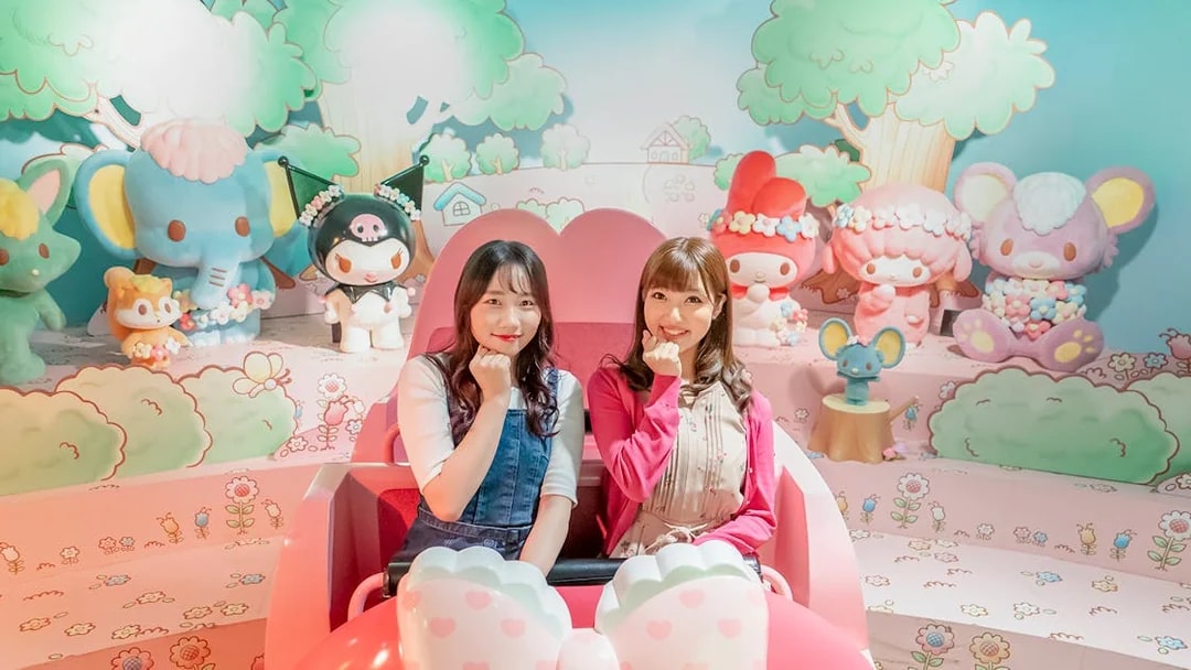 Visitors enjoying a ride at Sanrio Puroland with character figures in the background.