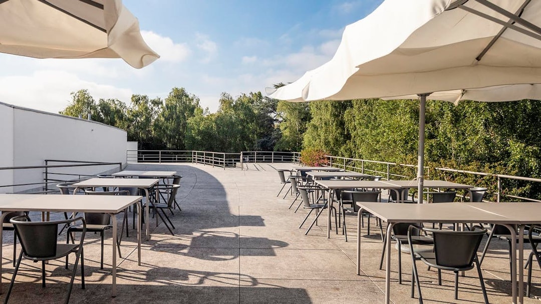 Outdoor terrace with tables and chairs at Serralves, Porto, surrounded by greenery.