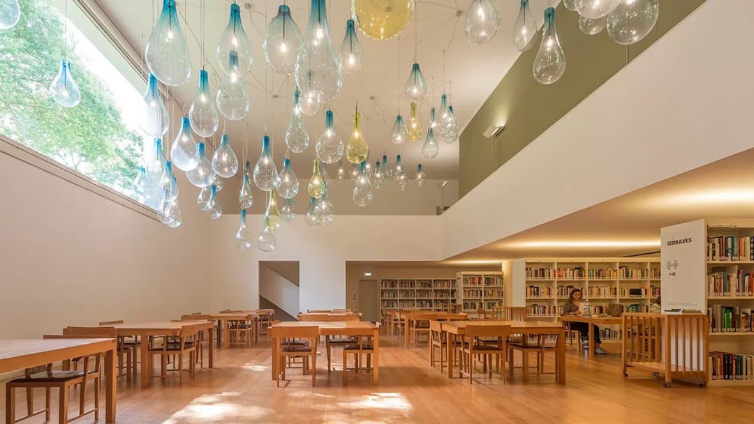Library interior at Serralves with unique hanging light fixtures and wooden tables.