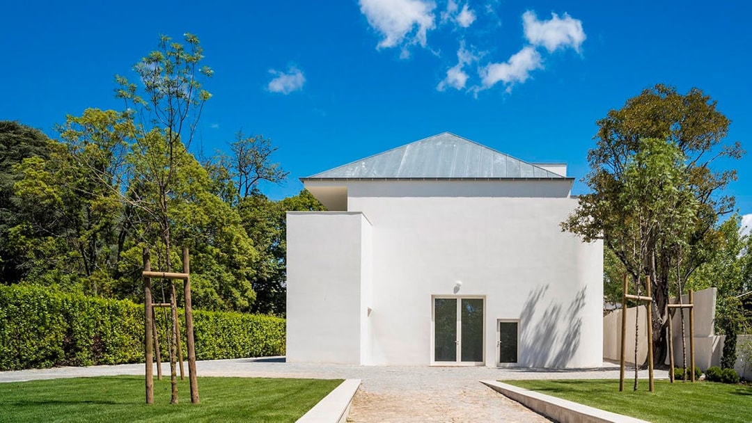 Modern white building at Serralves, Porto, surrounded by trees and a clear blue sky.