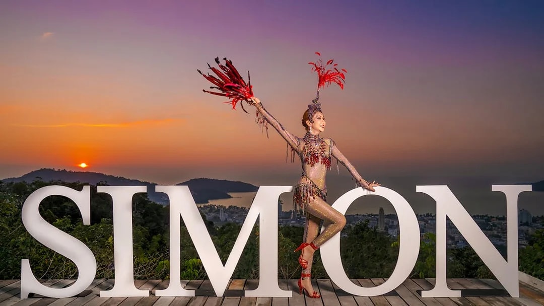 Performer in costume at Simon Cabaret Show with sunset backdrop in Phuket.