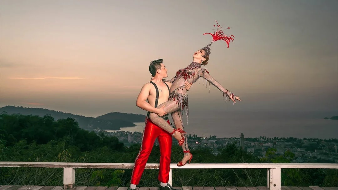 Performers in vibrant costumes at Simon Cabaret Show, Phuket, with scenic backdrop.