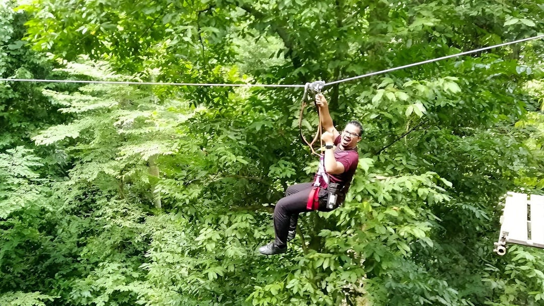 Person ziplining through lush forest at Skytrex Adventure Langkawi.