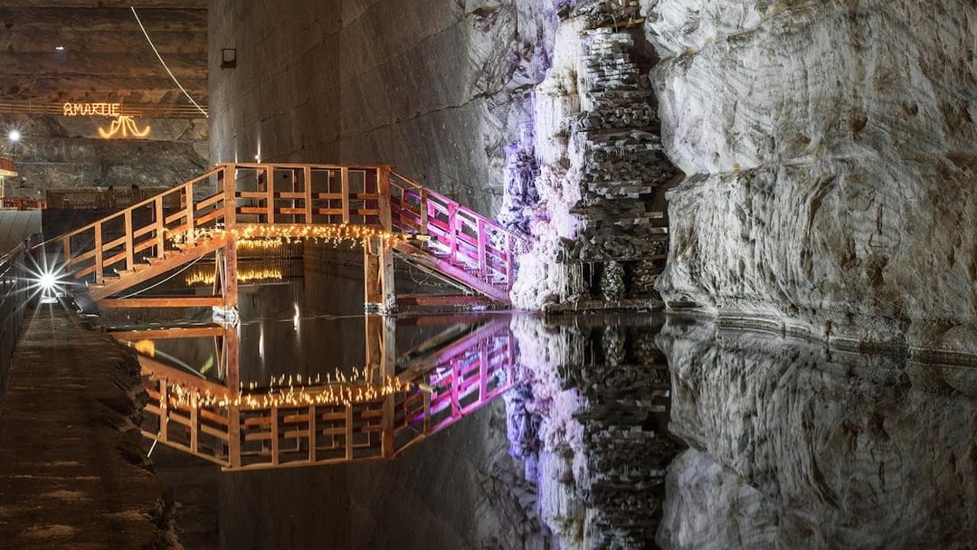 Wooden bridge with lights over water in Slanic Prahova Salt Mine, Bucharest.