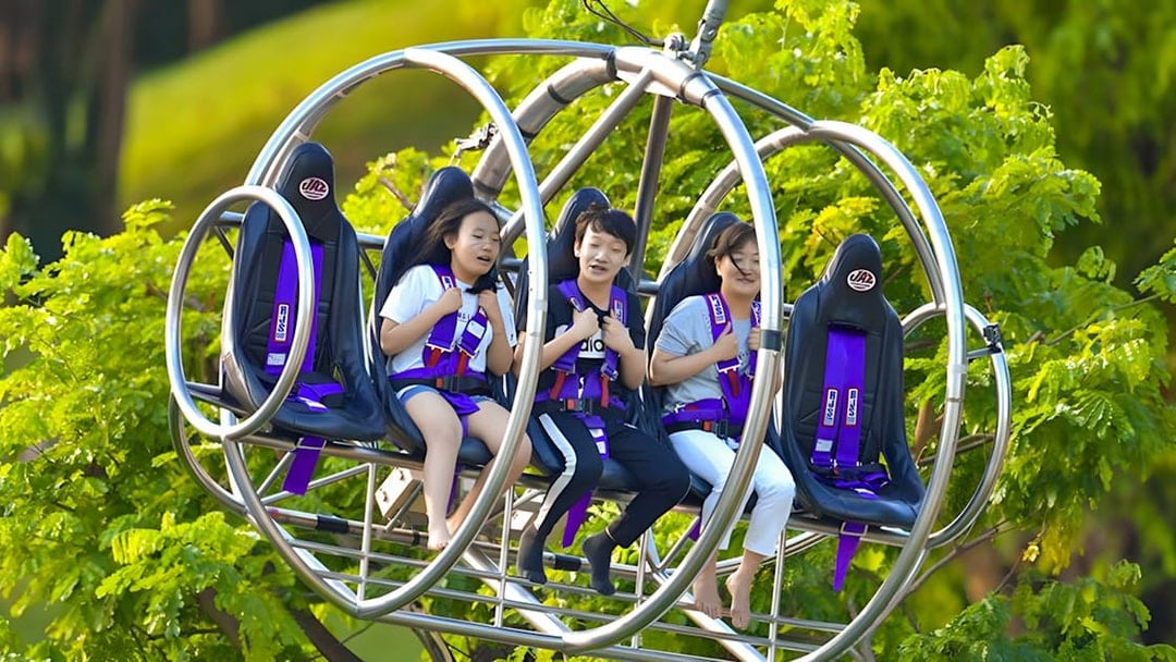 Visitors enjoying the Slingshot ride in Singapore amidst lush greenery.